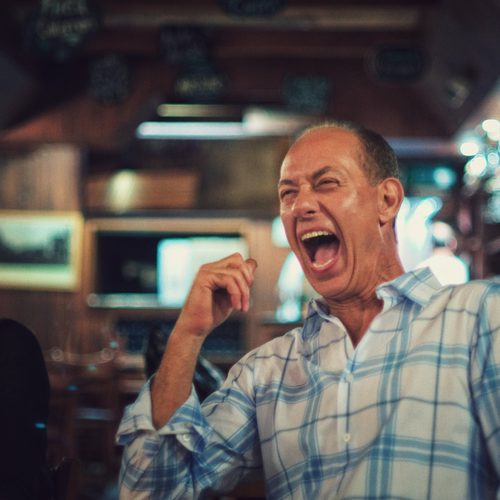 Medium shot of a man laughing at a party with a blurred background